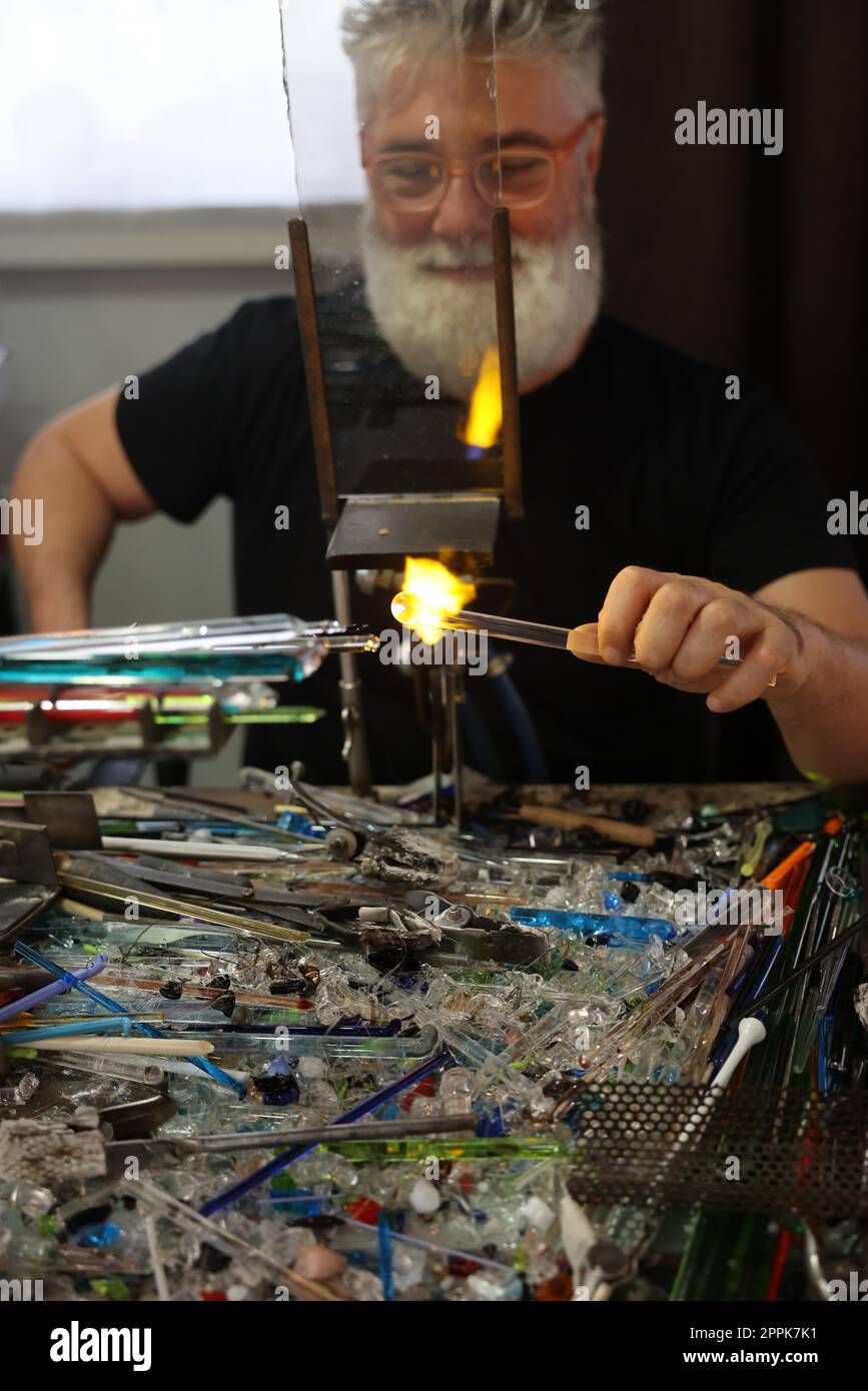 Lavoratore del vetro mentre modella il vetro con una fiamma ad altissima temperatura Foto Stock
