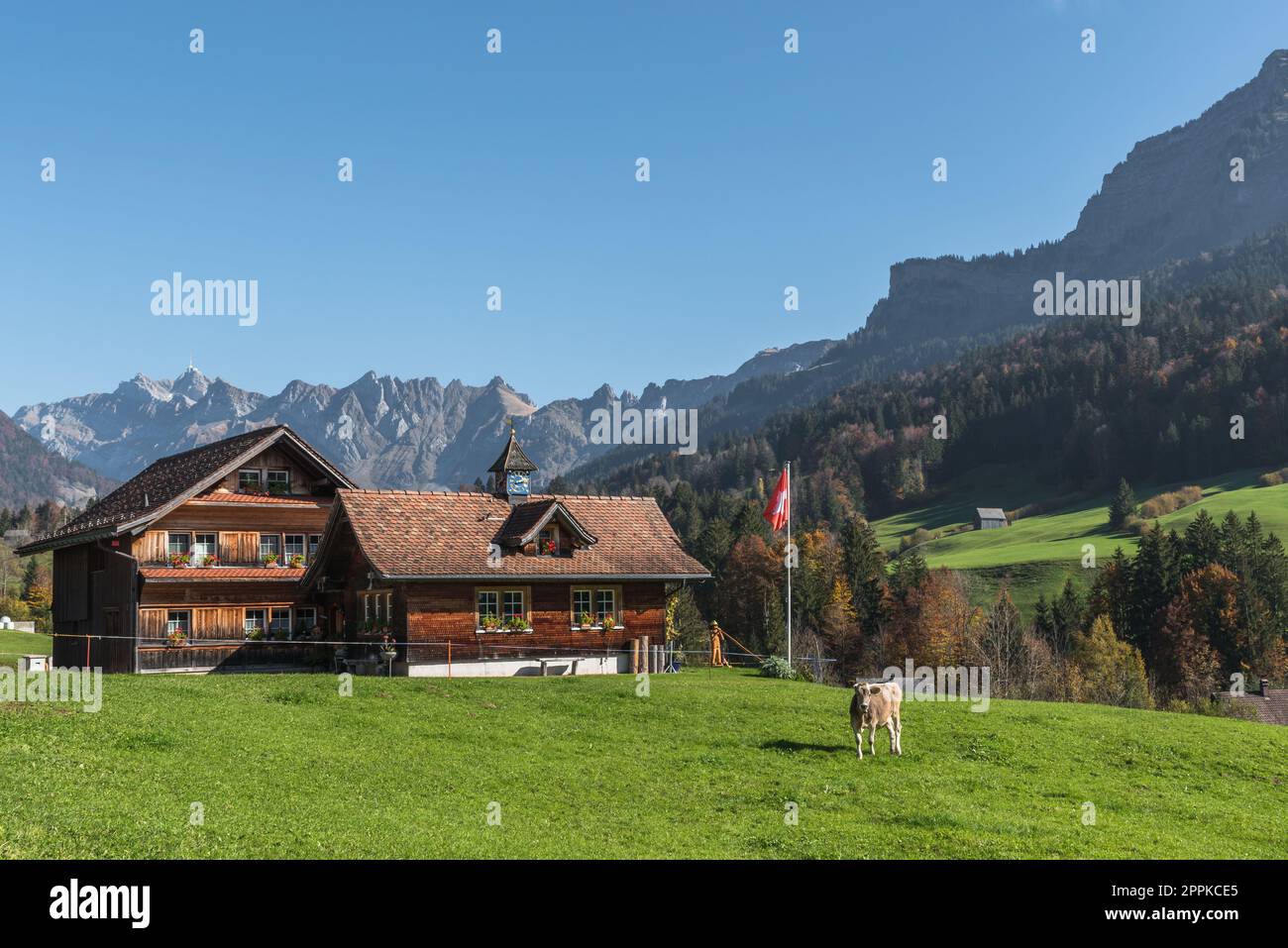 Ennetbuehl, Canton Sankt Gallen, Svizzera - 19 ottobre 2022. Tradizionale casale in legno con bandiera svizzera e vista sul Monte Saentis Foto Stock