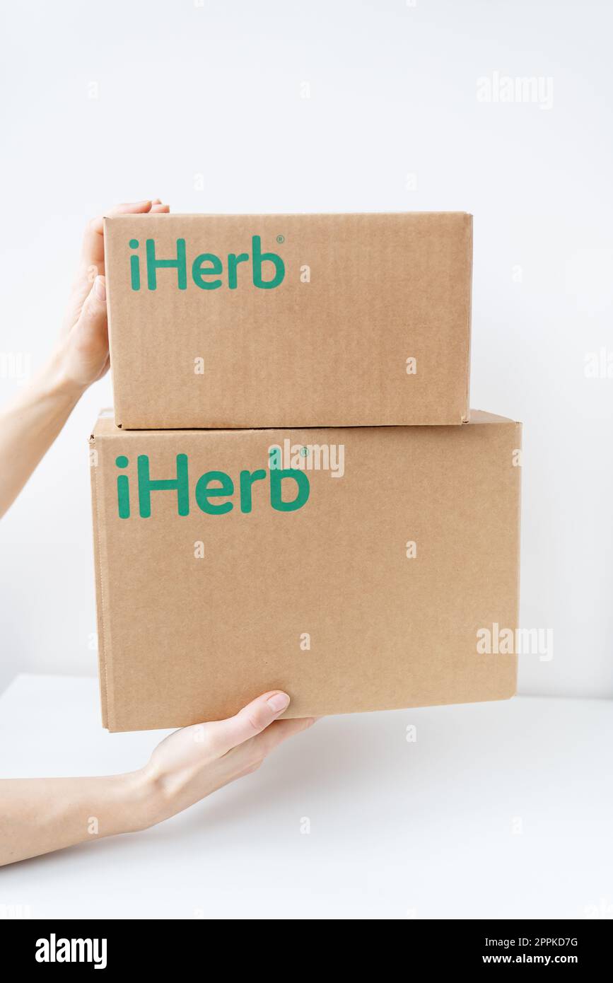 Kiev, Ucraina-17 dicembre 2022:. Confezione IHerb nelle mani del corriere, consegna rapida alla porta. Ordinazione online, consegna di beni e vitamine per la salute. Foto Stock