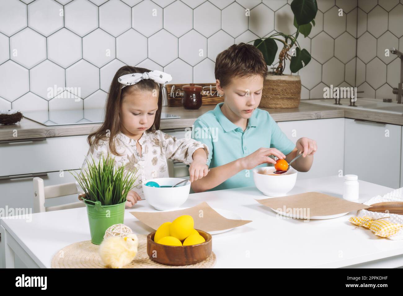 Ritratto concentrava due bambini piccoli, ragazzo, ragazza, colorare le uova di gallina di Pasqua. Assorbimento del colore. Primo piano Foto Stock