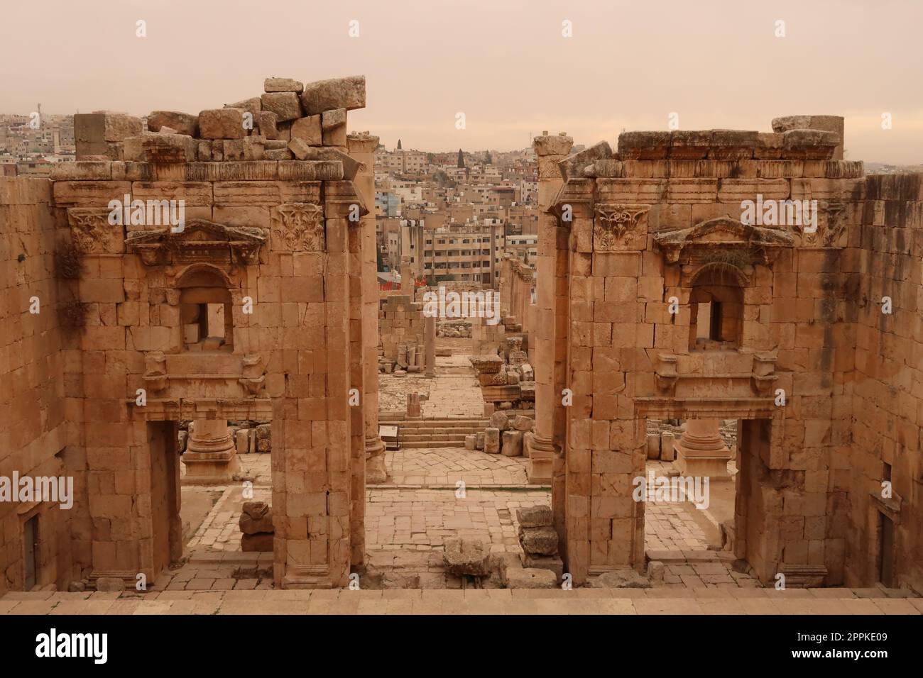 Porta d'ingresso al Tempio di Artemide, Propileo del Santuario di Artemide con la moderna città di Jerash sullo sfondo, Gerasa, Giordania Foto Stock