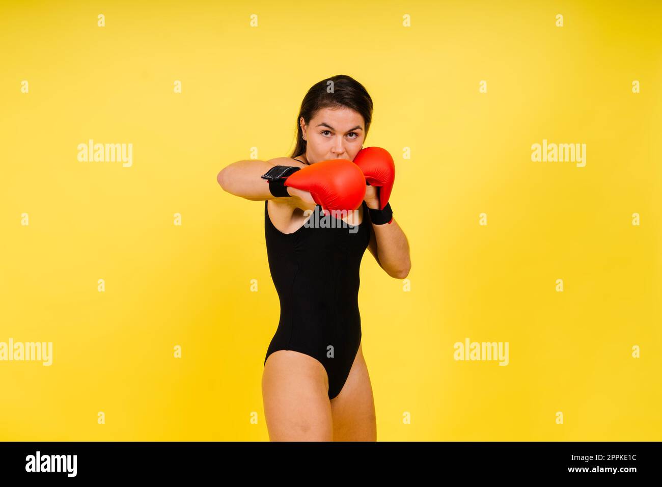 Forte sportivo in guanti da boxe preparati per il calcio alto. Isolato su sfondo bianco, rosso, giallo Foto Stock