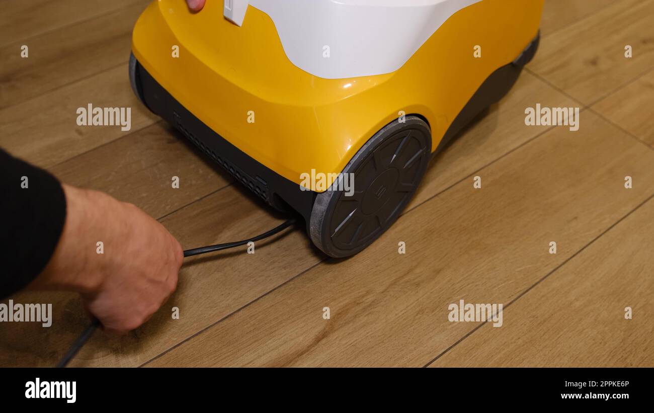 Cavo di imballaggio uomo caucasico dell'aspirapolvere all'interno della custodia. Uomo arrabbiato che cerca di imballare il cavo attaccato nell'aspirapolvere. Foto Stock