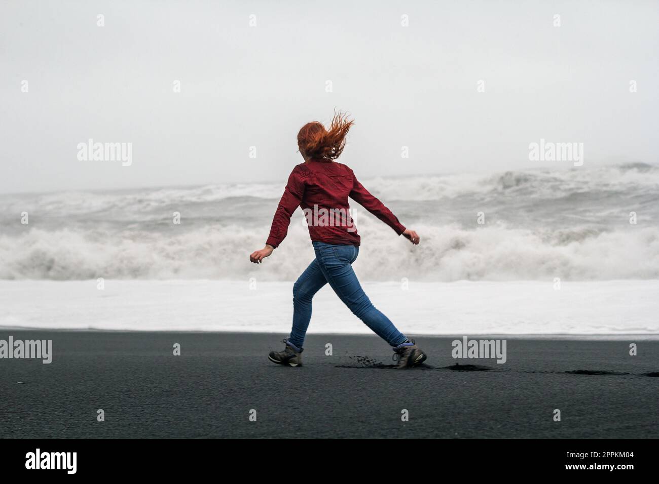 Giovane donna che corre lungo la spiaggia Islanda fotografia panoramica Foto Stock