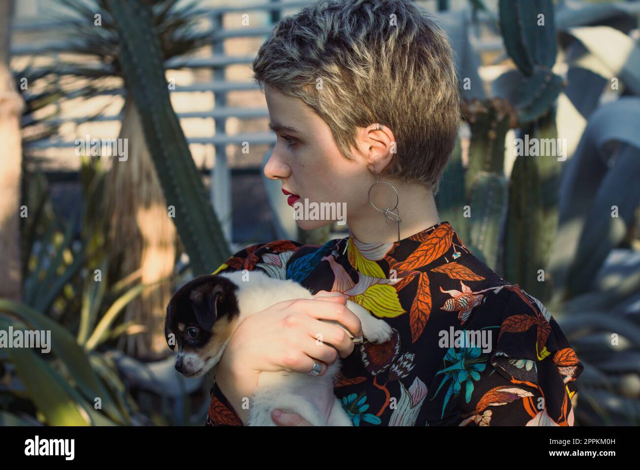 Primo piano attraente donna che tiene piccolo cucciolo in giardino ritratto immagine Foto Stock