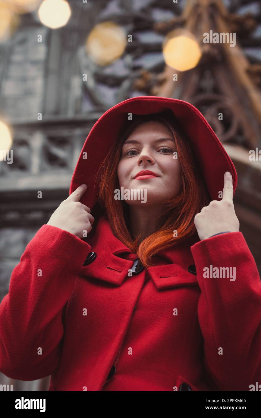Primo piano donna fiduciosa in cappotto rosso sul ritratto città strada Foto Stock