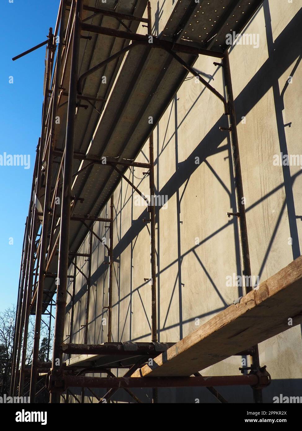 Impalcature su una nuova casa a un piano. La facciata funziona. Creazione di affari. Basso edificio privato. Intonacare il muro di un edificio. Edificio di negozi. Strutture per la produzione di metalli. Foto Stock