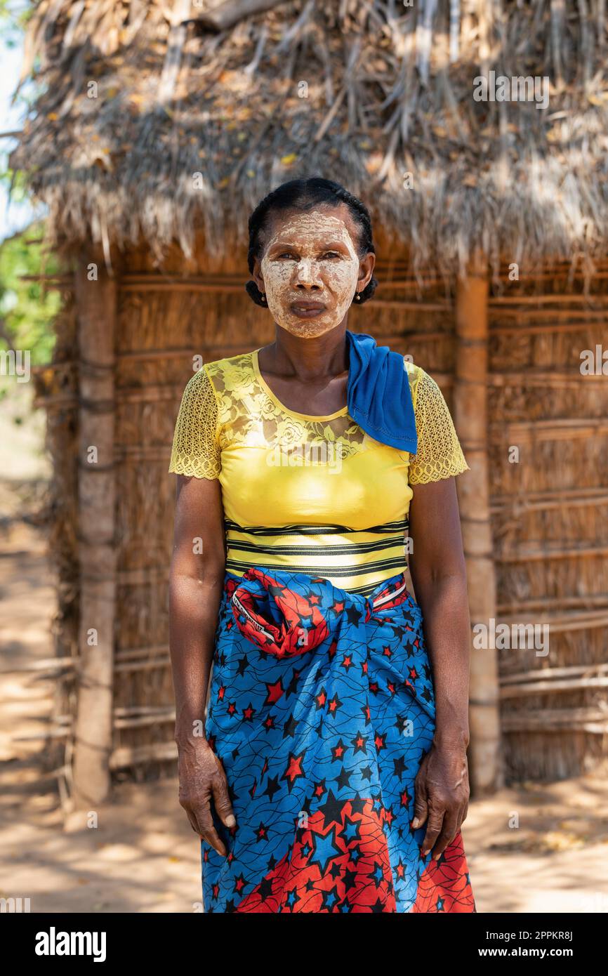 Donna malgascia di fronte alla sua capanna con un volto dipinto tradizionalmente. Le donne malgasce dipingono i loro volti per proteggerli dal sole. Foto Stock