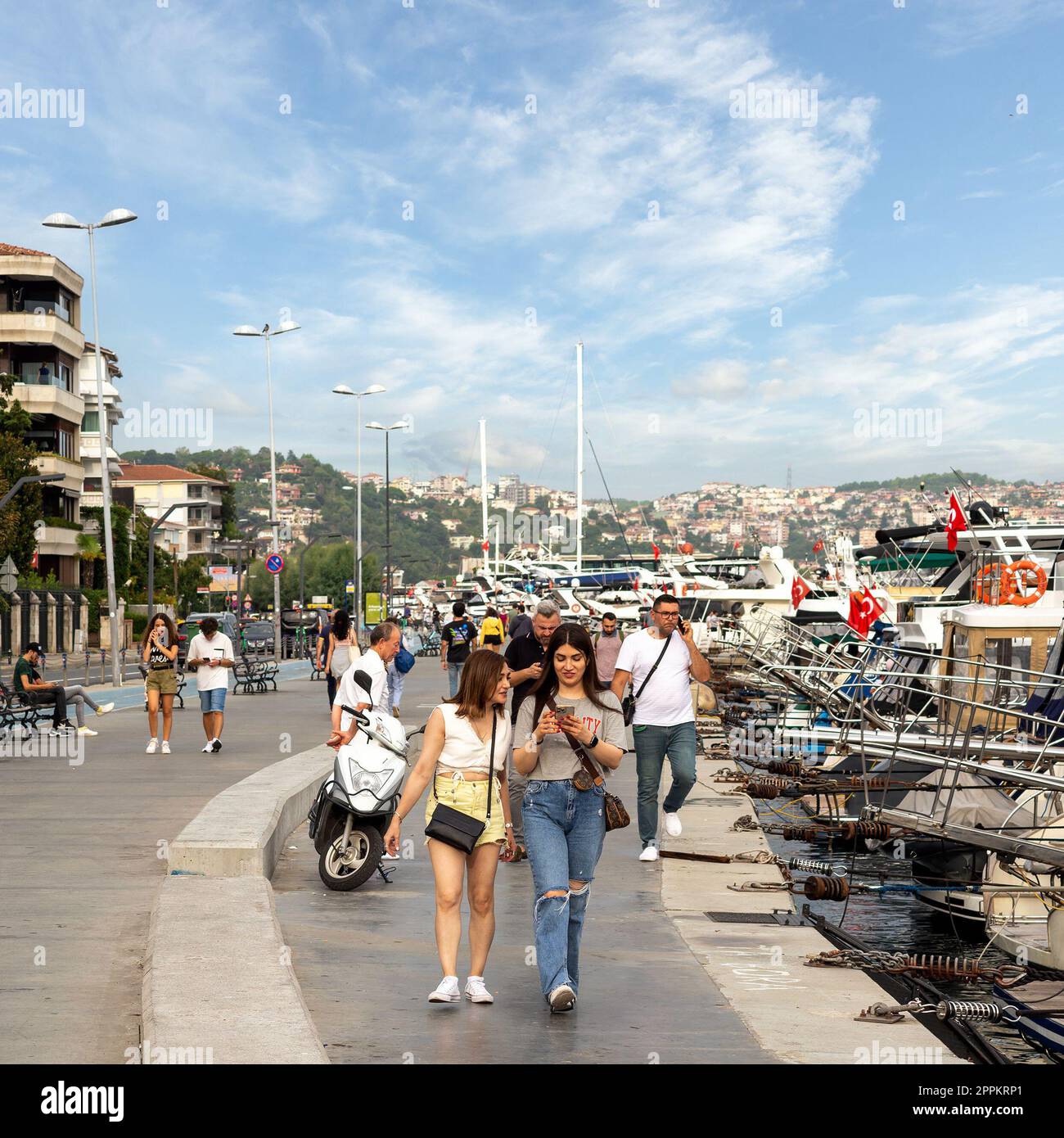 Persone che camminano lungo il Bosforo tra i quartieri di Bebek e Hisari, accanto a barche e yacht attraccati, Istanbul, Turchia Foto Stock