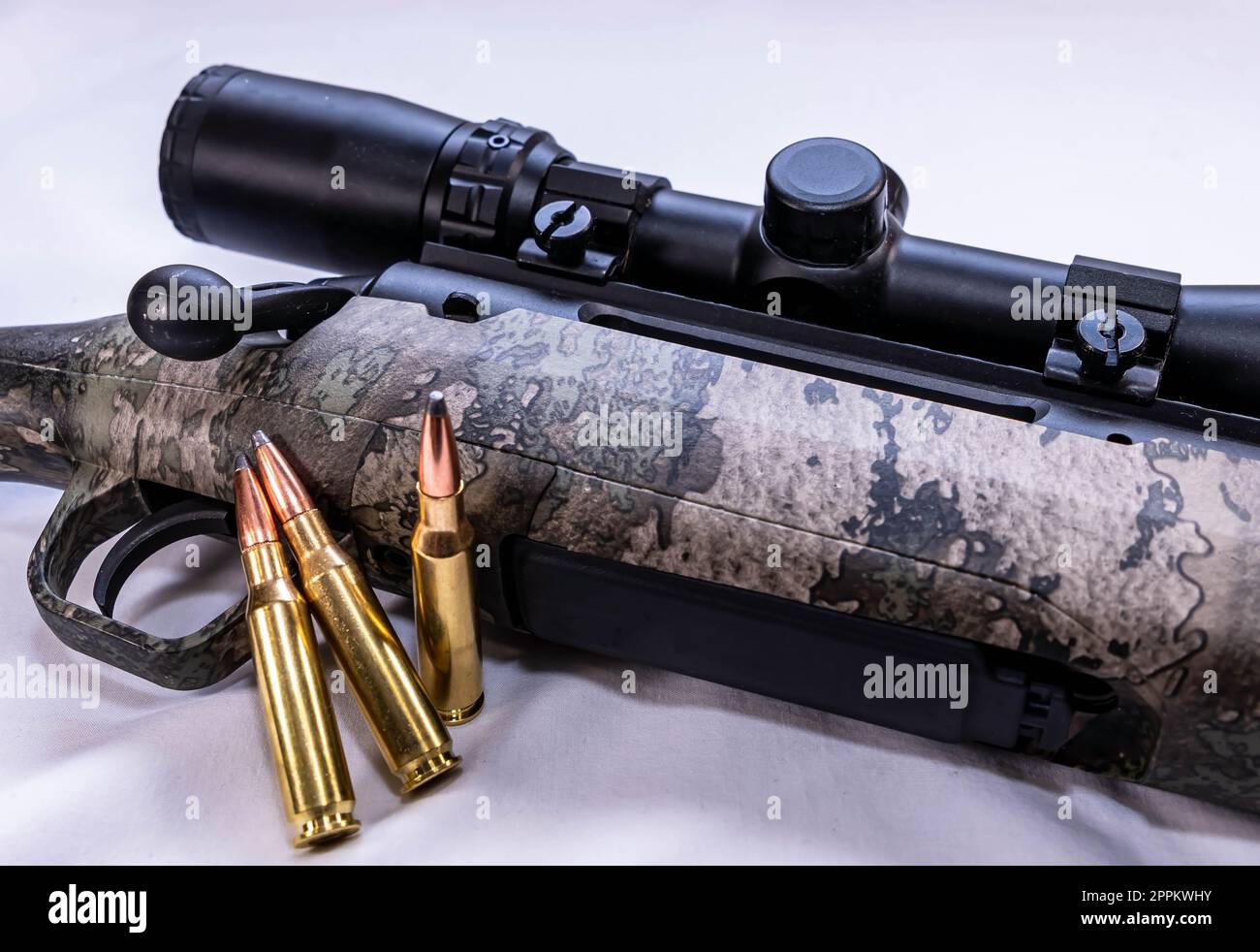 Un fucile da cervo ad alta potenza con un calcio camosintetico e tre pallottole su sfondo bianco Foto Stock