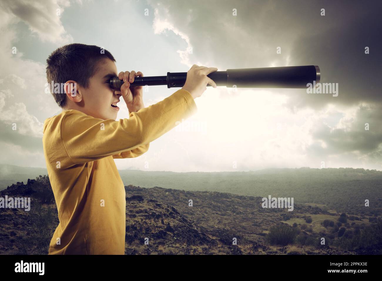 Un bambino con la lente di ingrandimento guarda lontano per una nuova avventura Foto Stock