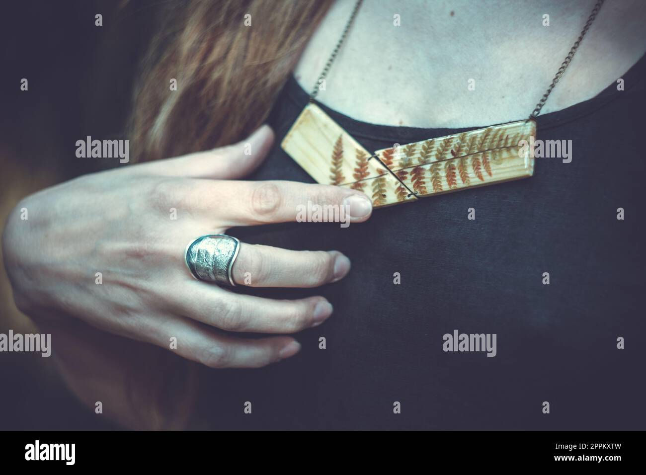 Primo piano donna con anello in metallo e pendente in legno concept foto Foto Stock