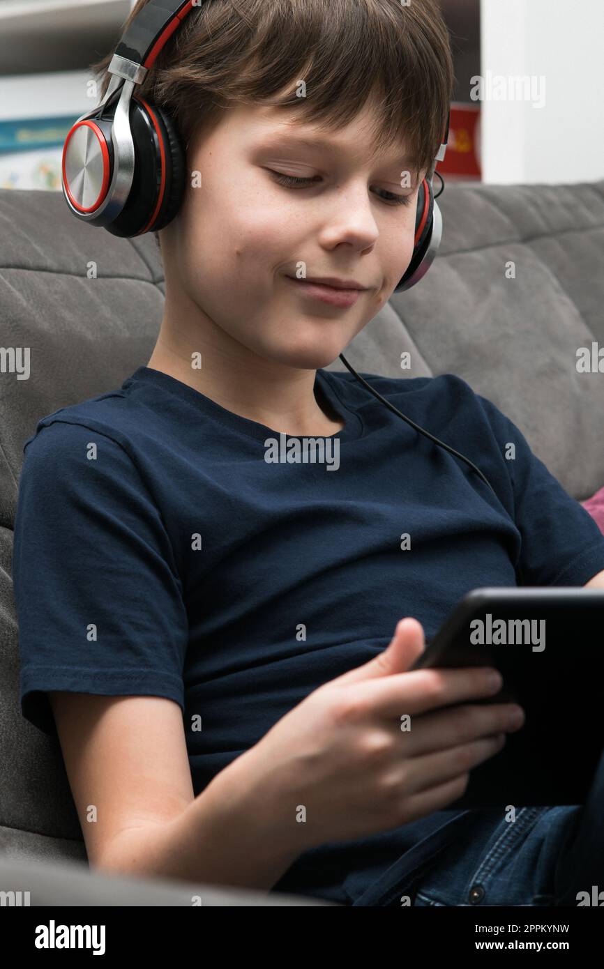 Ritratto di Happy Boy con un tablet digitale. I bambini con le cuffie giocano a videogame su gadget o ascoltano musica. Foto Stock