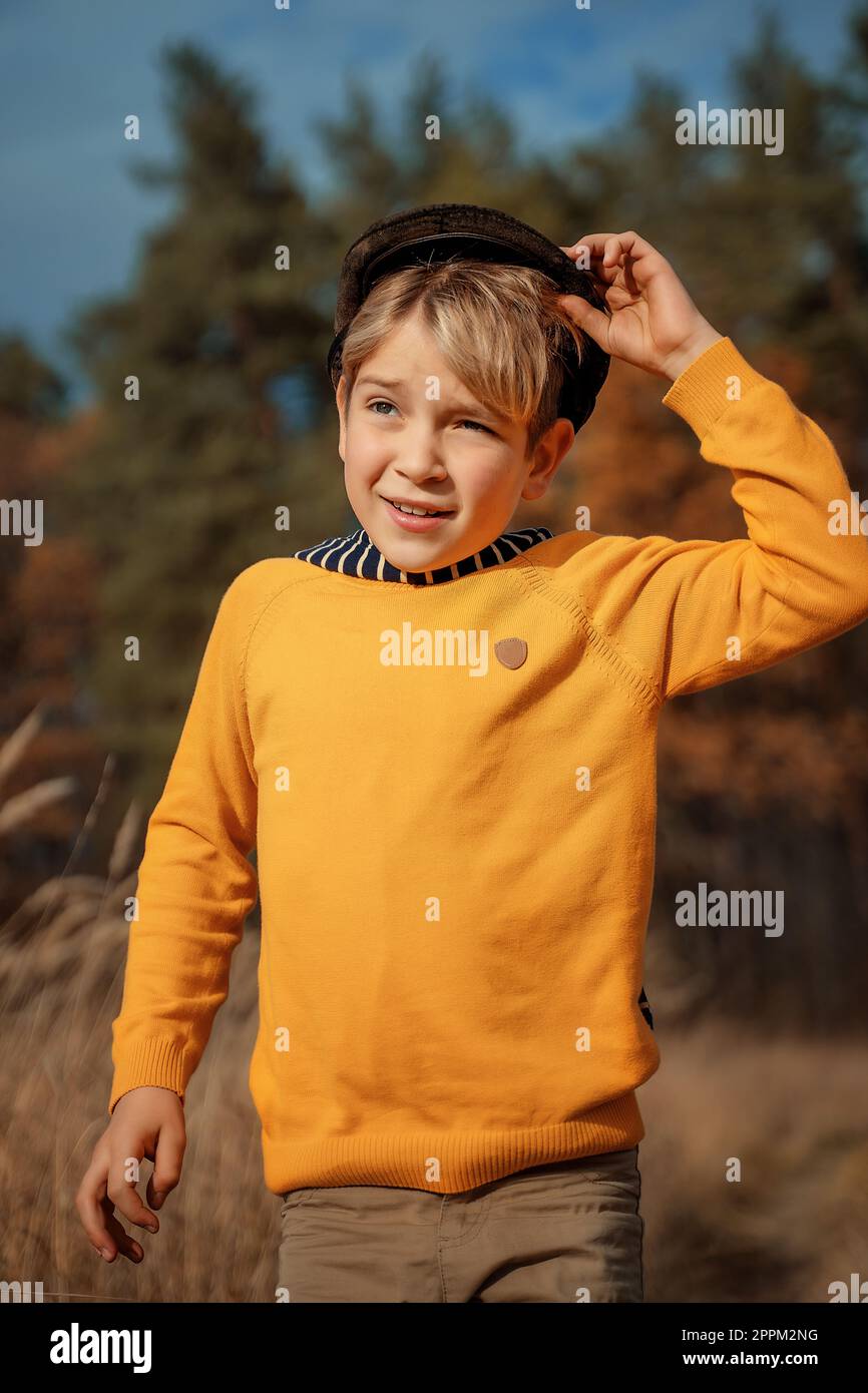 Moda per bambini, stile retrò. Un ragazzino sorridente in un cappotto retrò e cappello si alza e sorride. Spazio di copia Foto Stock