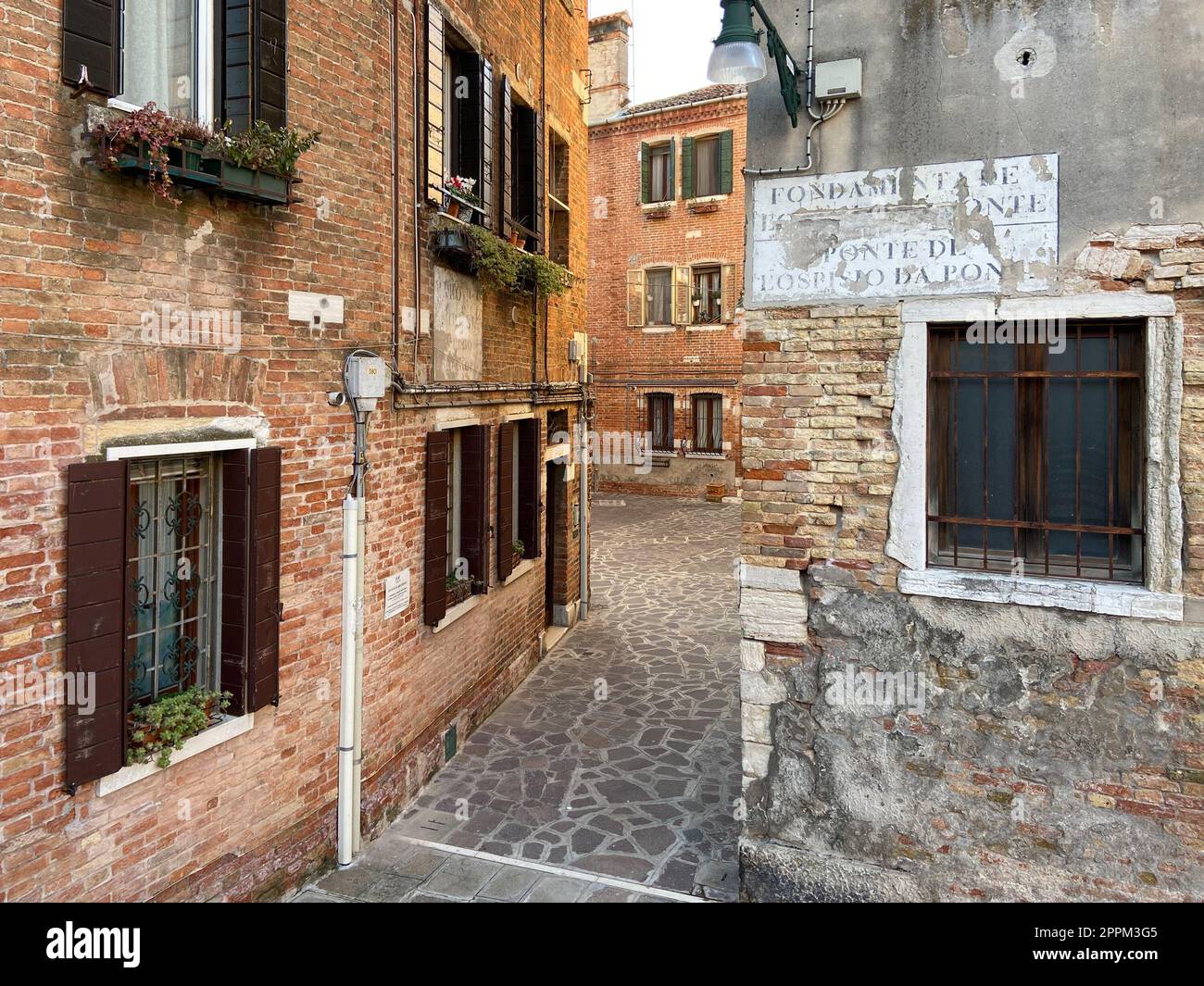 Strada stretta con pavimentazione in pietra nella città di Venezia Foto Stock