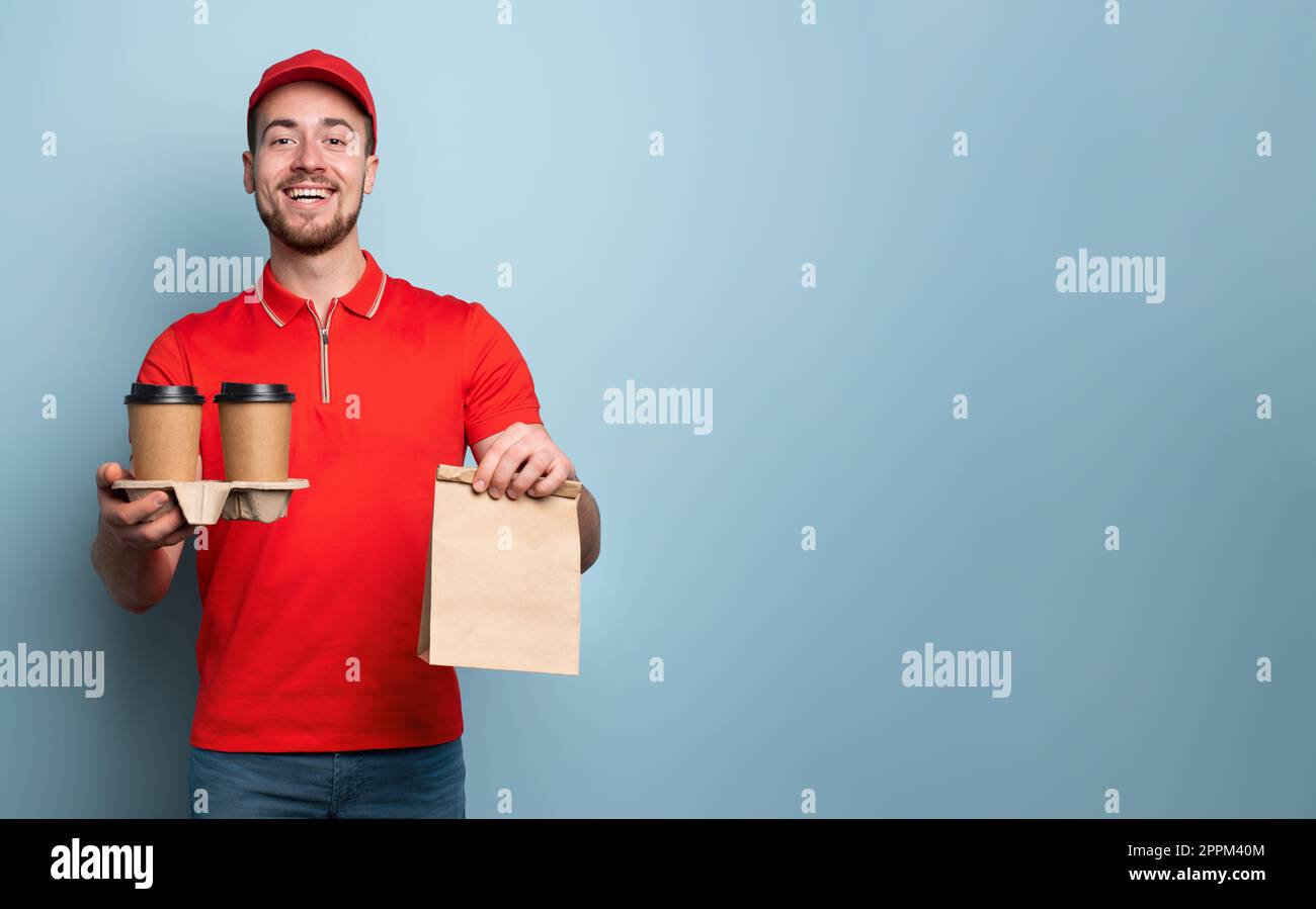 Il corriere è felice di consegnare caffè e cibo caldi. Sfondo ciano Foto Stock