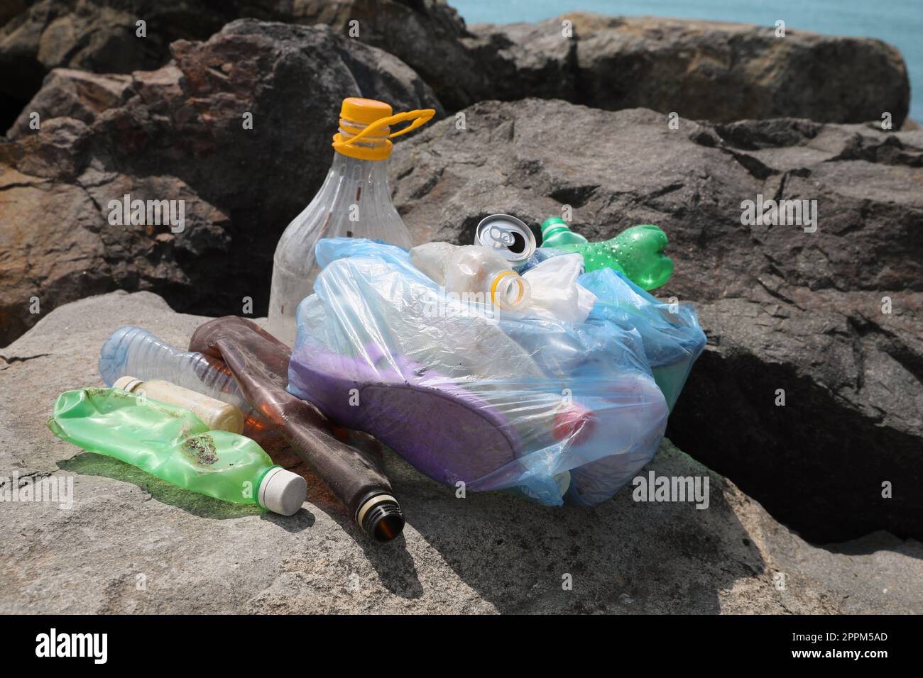 Spazzatura su pietre vicino al mare. Concetto di inquinamento ambientale Foto Stock