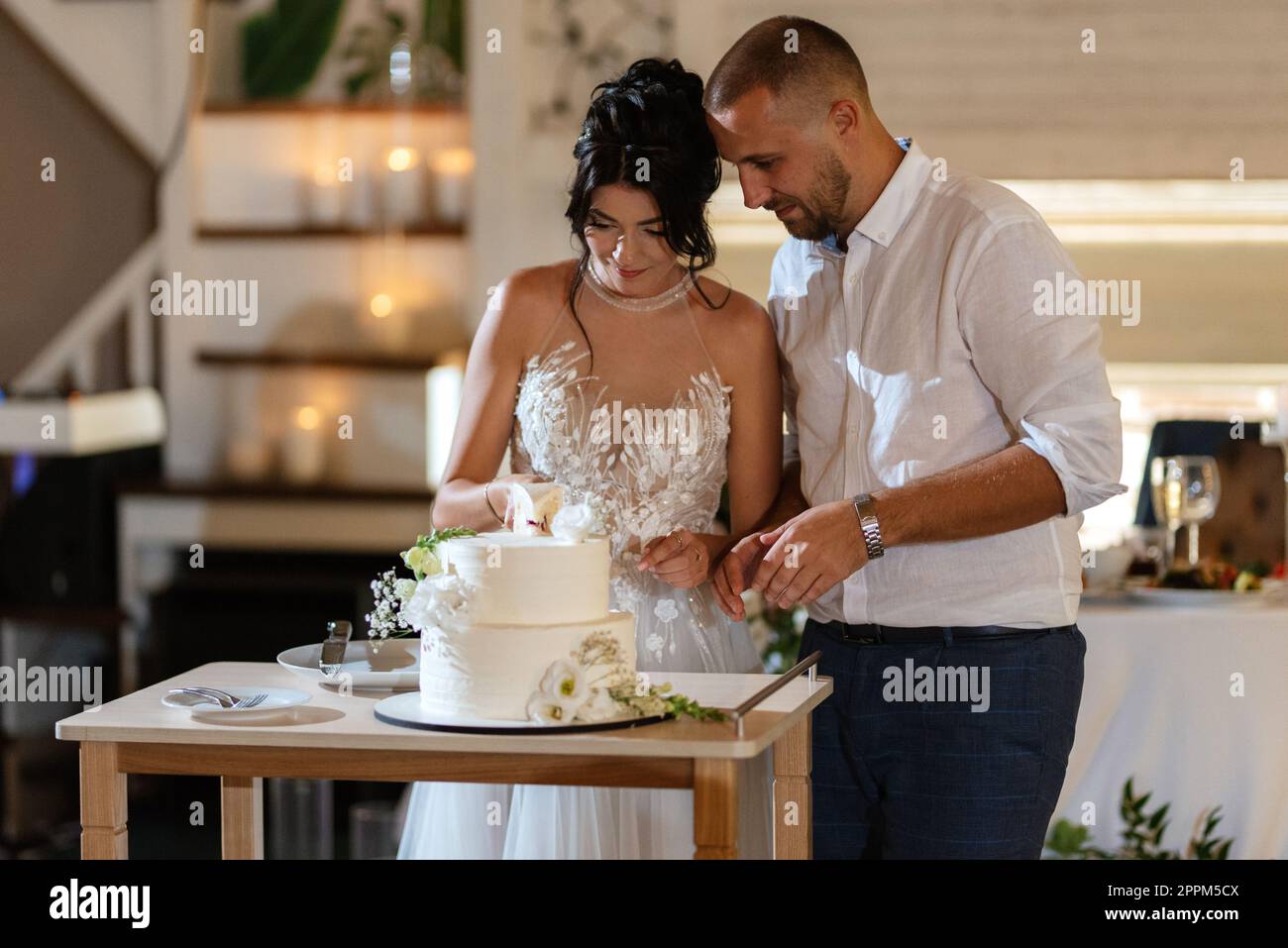 gli sposi novelli tagliano e assaggiano la torta nuziale Foto Stock
