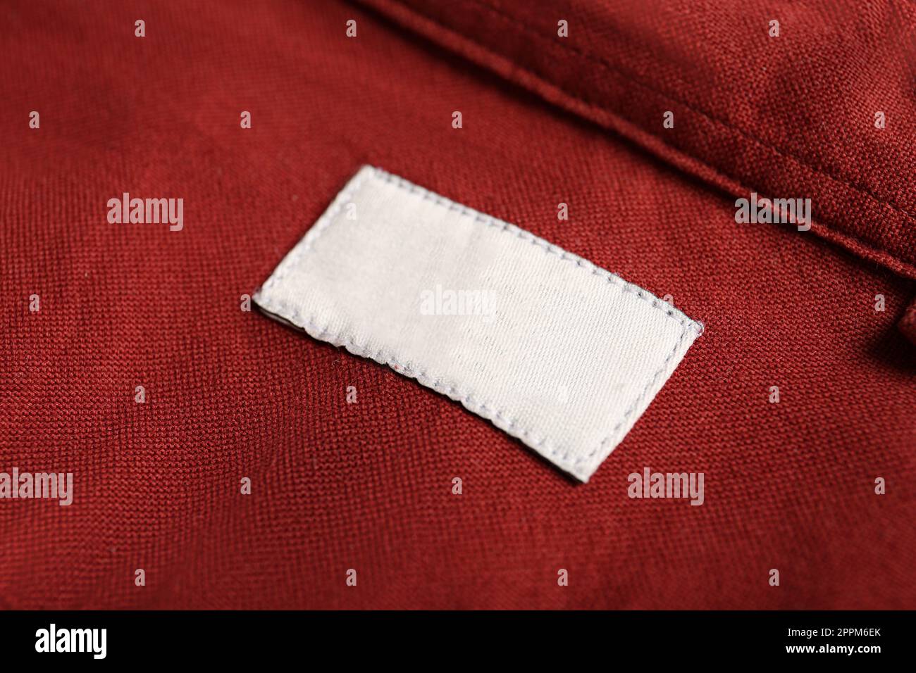 Etichetta di abbigliamento vuota su camicia rossa, primo piano Foto Stock