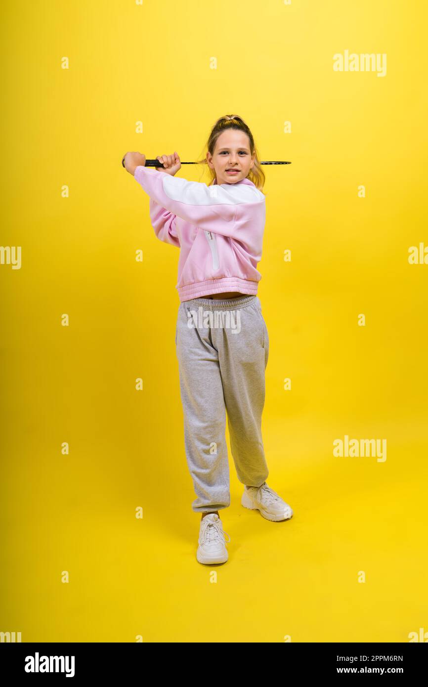 Foto di studio di lunghezza intera di una ragazza di dieci anni con racchetta di badminton e isolata sul giallo. Foto Stock