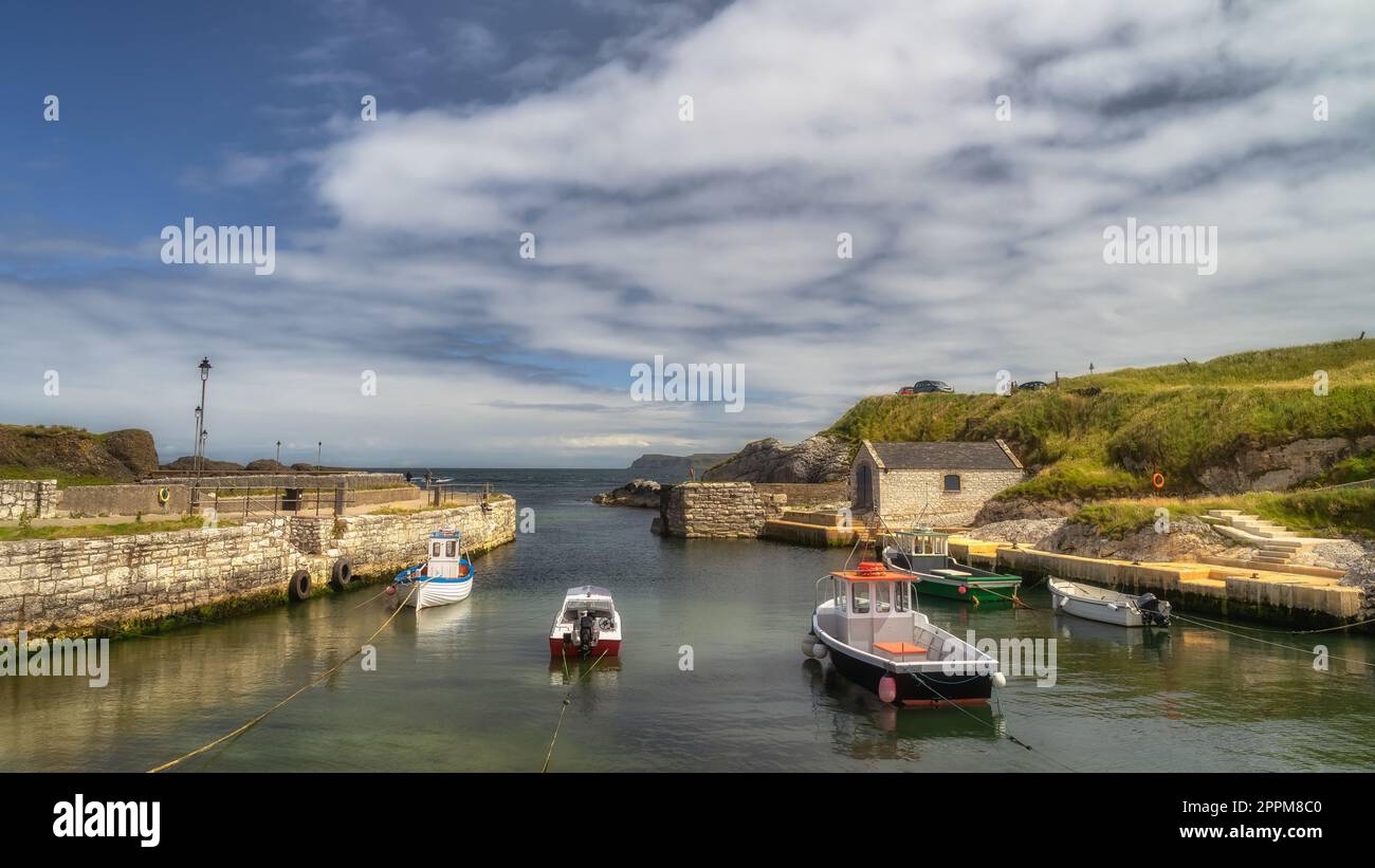 Piccolo porto di Ballintoy con molo in pietra e barche ormeggiate, Irlanda del Nord Foto Stock