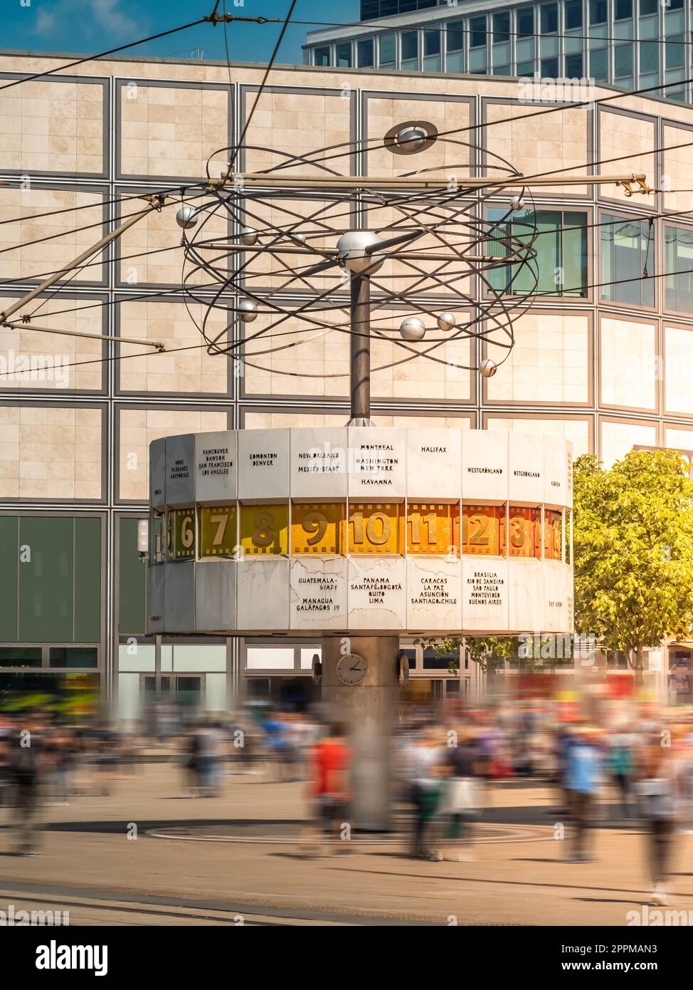 Famoso orologio mondiale ad Alexanderplatz, Berlino, Germania, con persone che camminano davanti, lunga esposizione, al tramonto, ripresa verticale Foto Stock