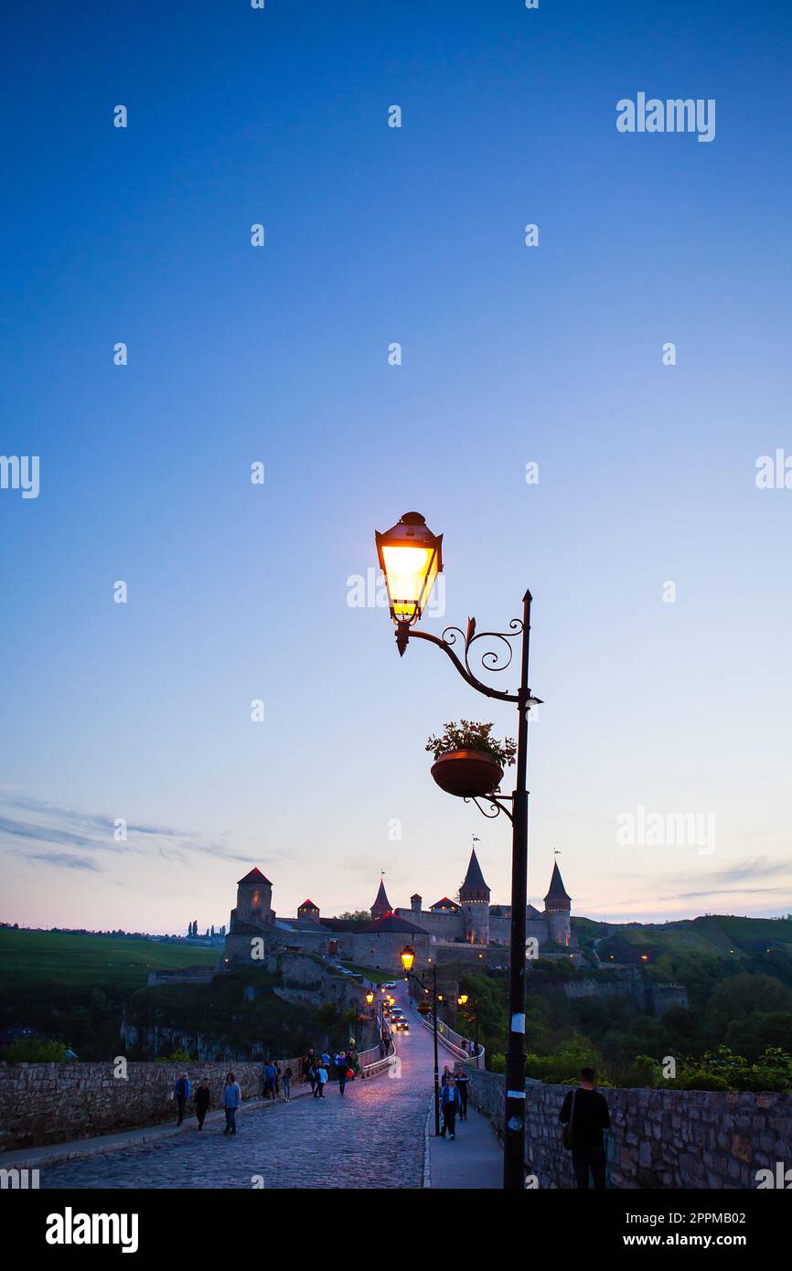 Kamianets-Podilskyi è una città romantica, con una splendida vista della città serale, le lanterne illuminano il ponte e la lanterna da vicino. Una pittoresca vista estiva dell'antico castello-fortezza di Kamianets-Podilskyi, regione di Khmelnytskyi, Ucraina. Foto Stock