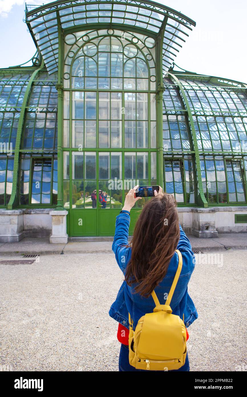 Una giovane ragazza tiene in mano un telefono e scatta una foto di un bell'edificio nel Parco Schonbrunn di Vienna. Foto Stock