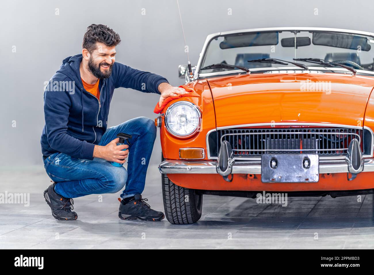 un uomo tratta la carrozzeria con uno straccio e sostanze chimiche Foto Stock