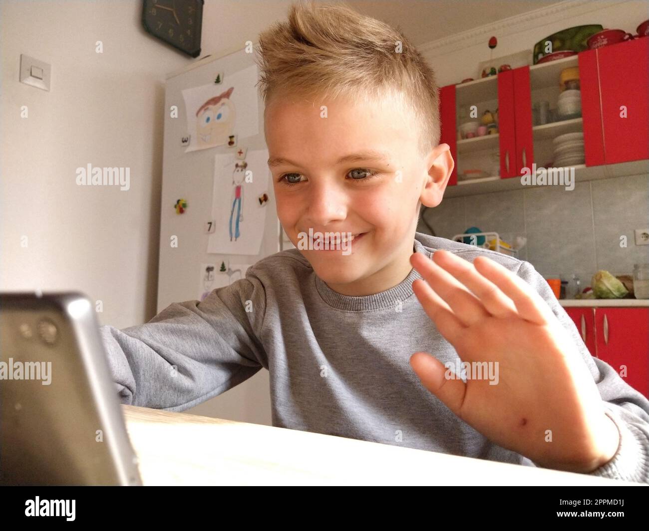 Sremska Mitrovica, Serbia, 20 maggio 2020 ragazzo biondo con portatile. Il bambino guarda il monitor e agita la mano come un saluto Foto Stock