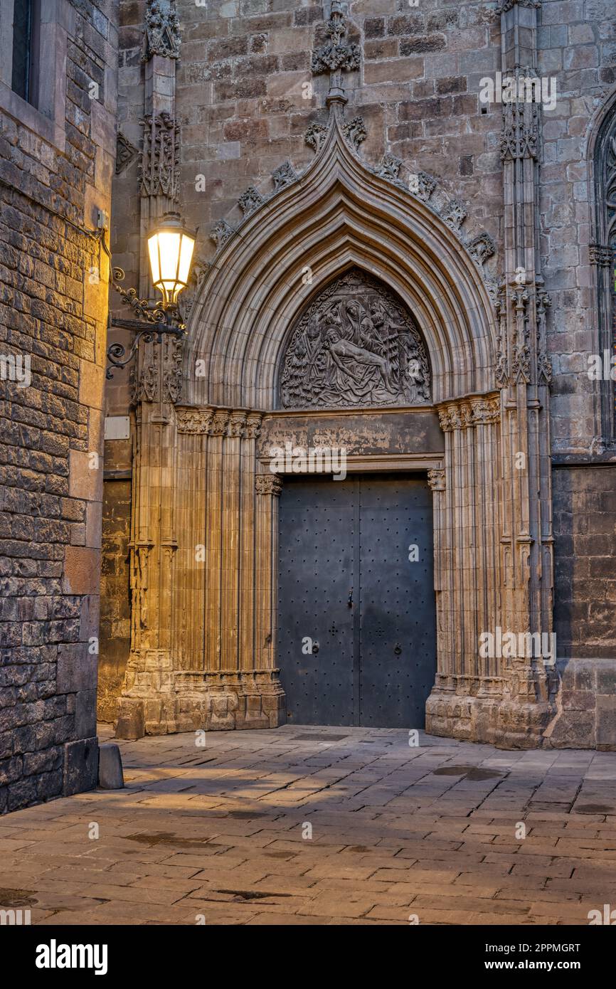 Via nel quartiere Gotico di Barcellona al crepuscolo con un ingresso laterale alla cattedrale Foto Stock