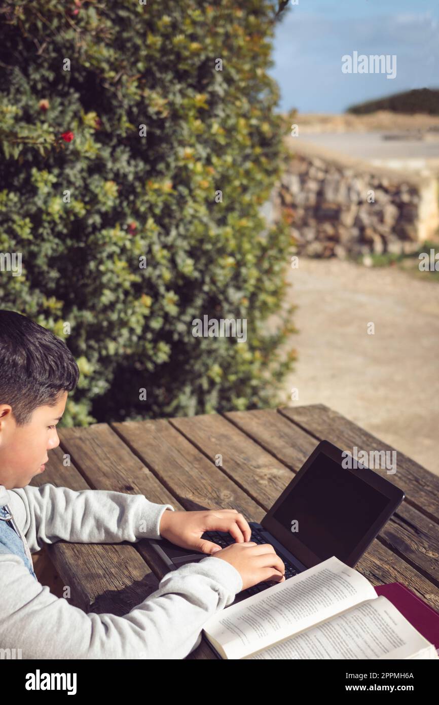 giovane studente latino, all'aperto, con un computer portatile seduto in un parco Foto Stock