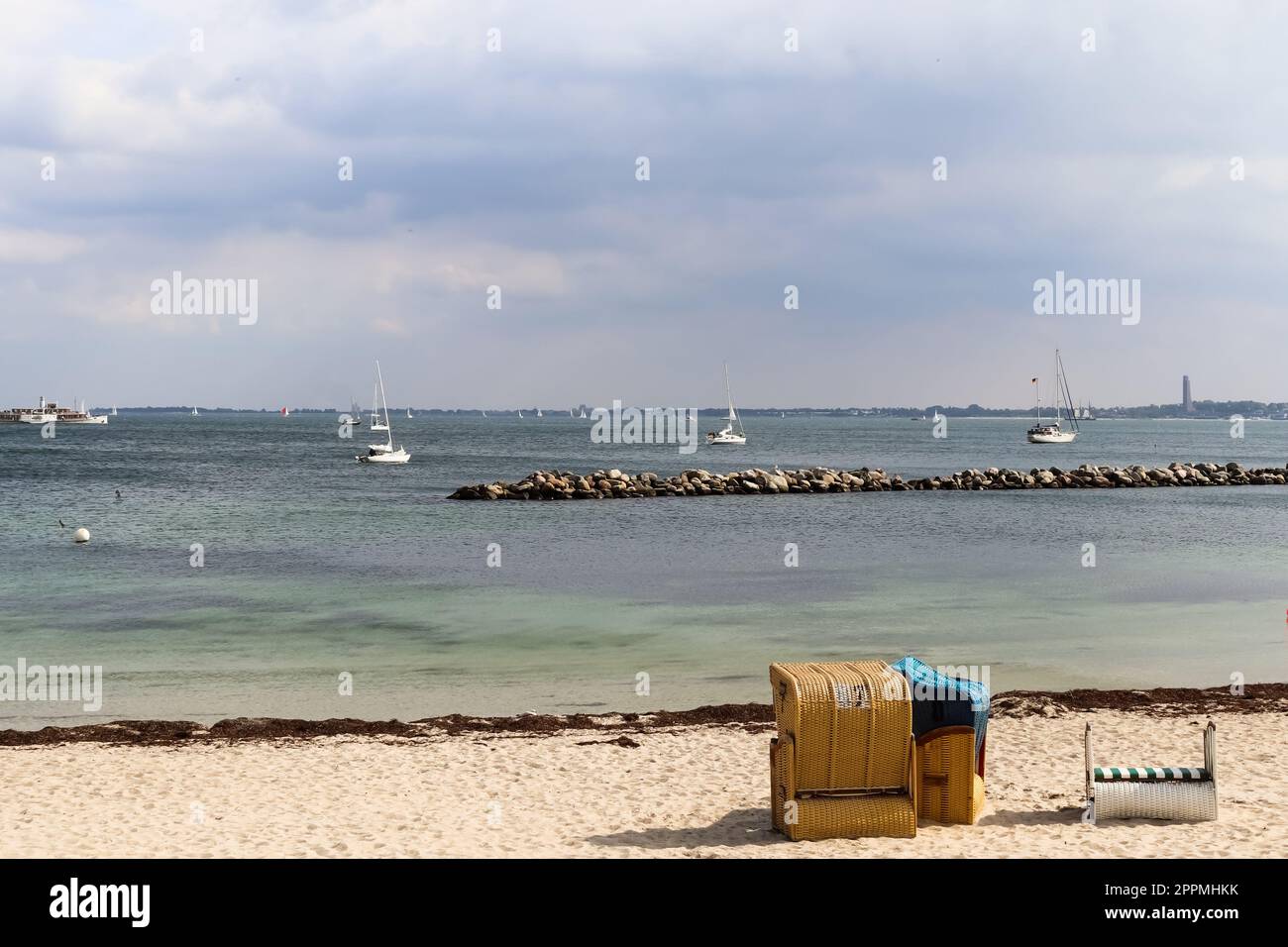 Molte barche a vela su una spiaggia sabbiosa in Germania con alcune sedie a sdraio. Foto Stock