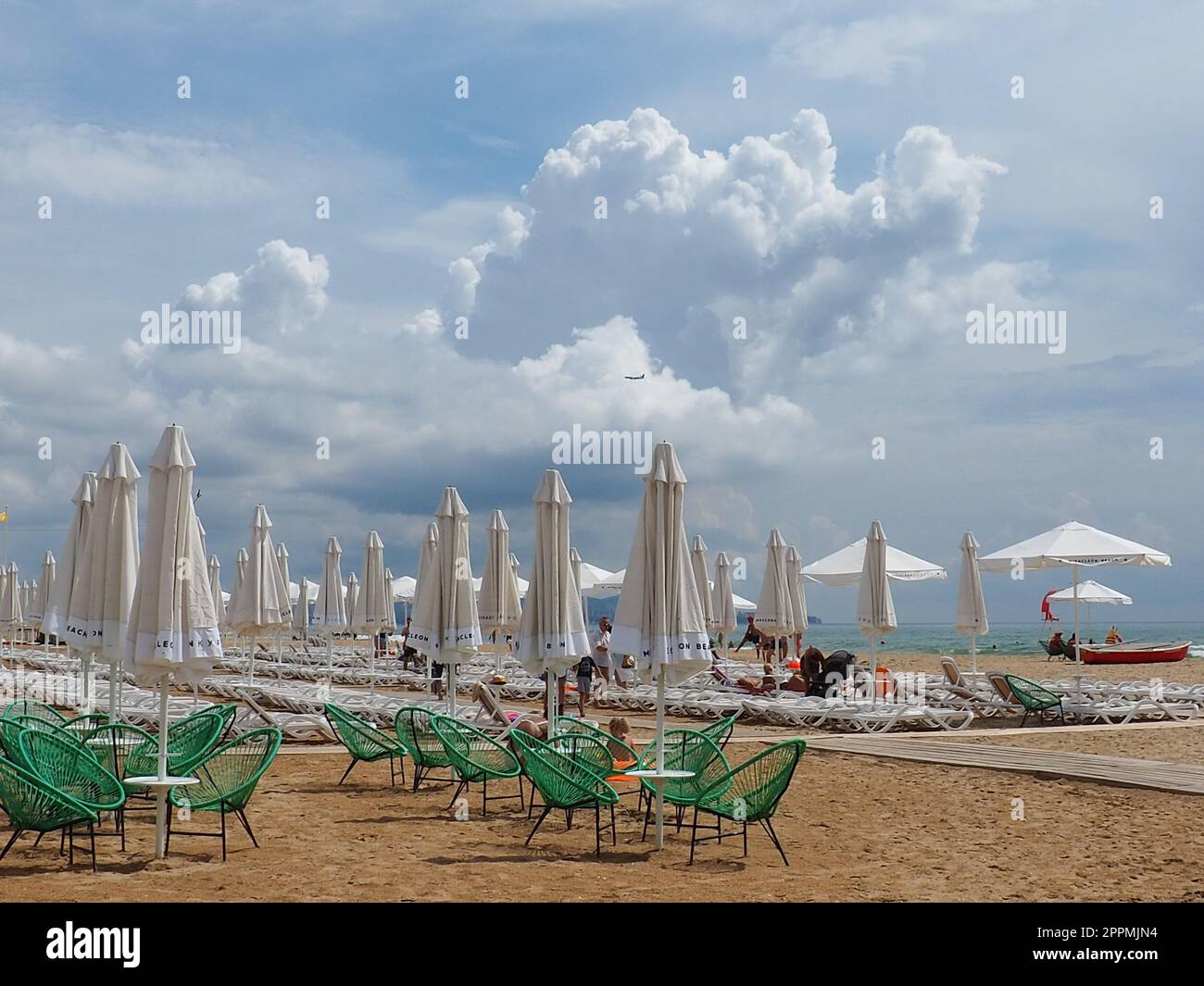 Anapa, Russia, 15 agosto 2021 sedie a sdraio e ombrelloni sulla spiaggia di sabbia dopo la pioggia. Stagione balneare. Caffè sulla spiaggia con sedie in vimini. Turisti che camminano. Un avvertimento tempesta. Nuvole di Cumulus Foto Stock