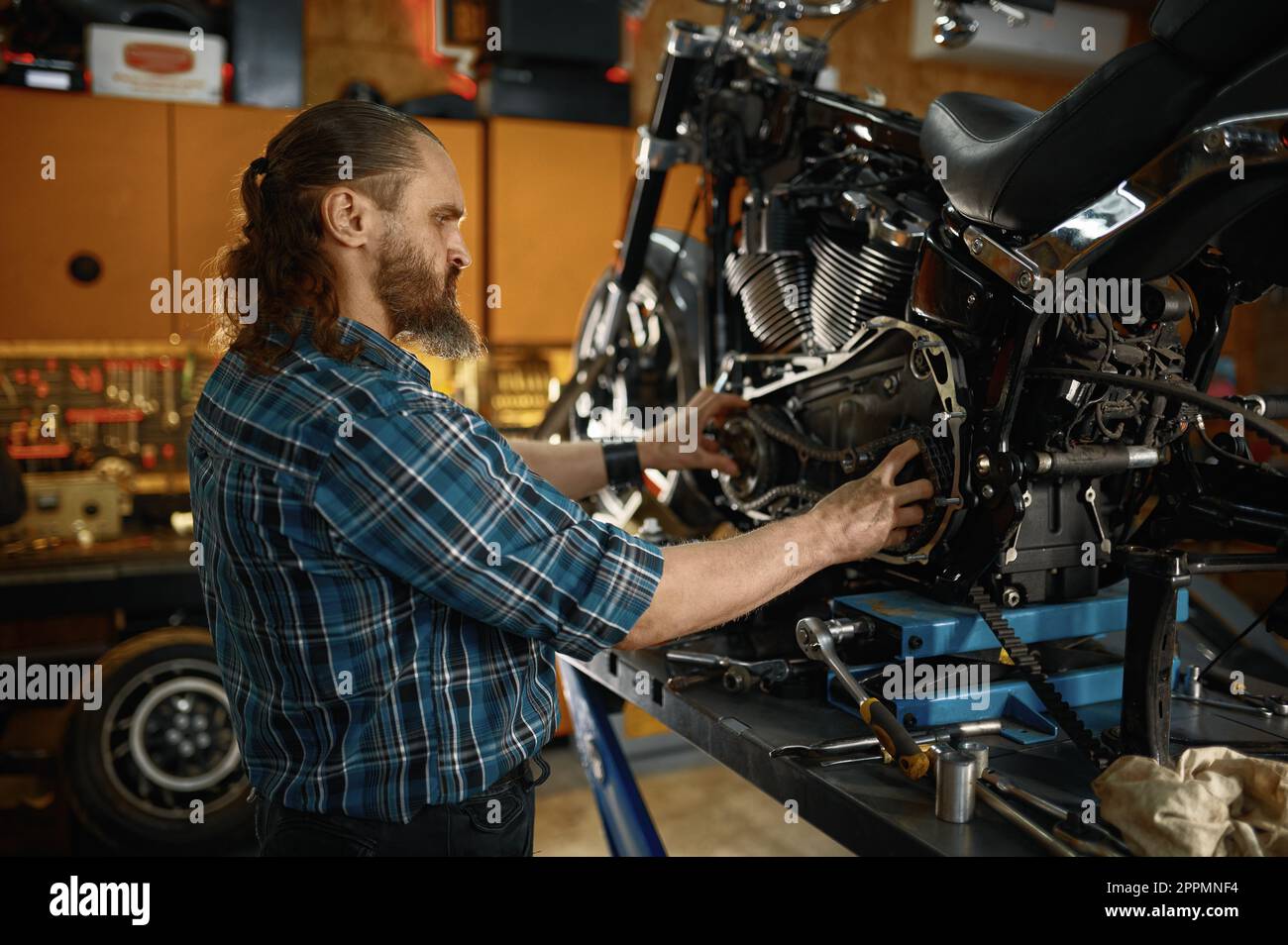 Uomo meccanico di fissaggio del motore di una motocicletta che lavora in officina Foto Stock