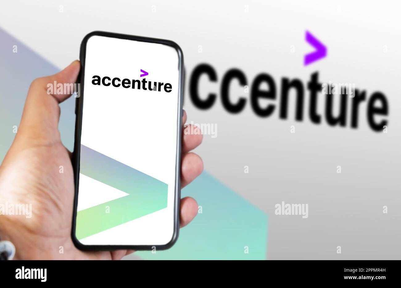 Mano che tiene un telefono con il logo Accenture visualizzato sullo schermo Foto Stock