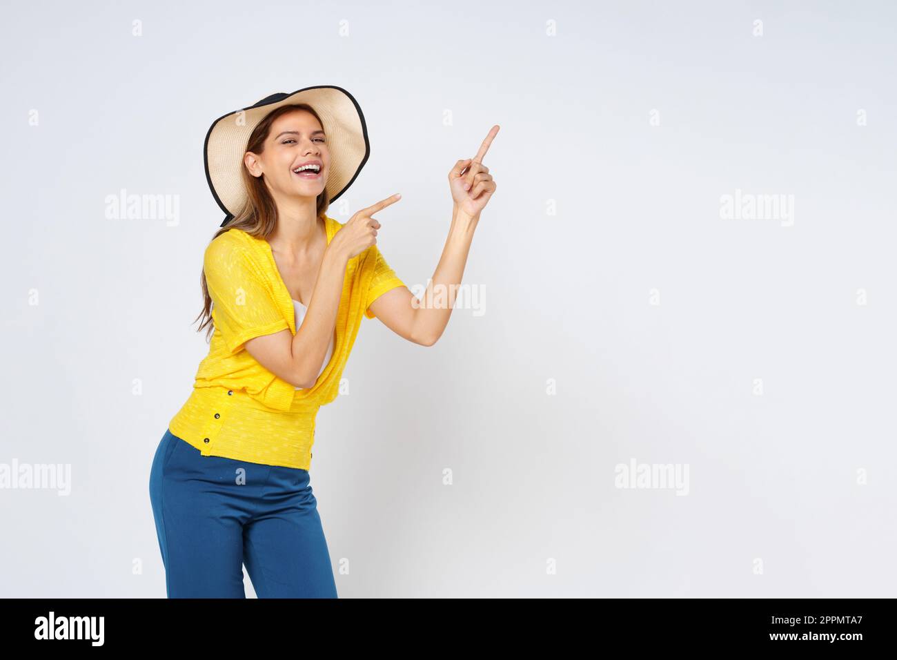 Giovane donna che indossa un cappello da sole e che indica uno spazio vuoto di copia isolato su sfondo bianco. Foto Stock