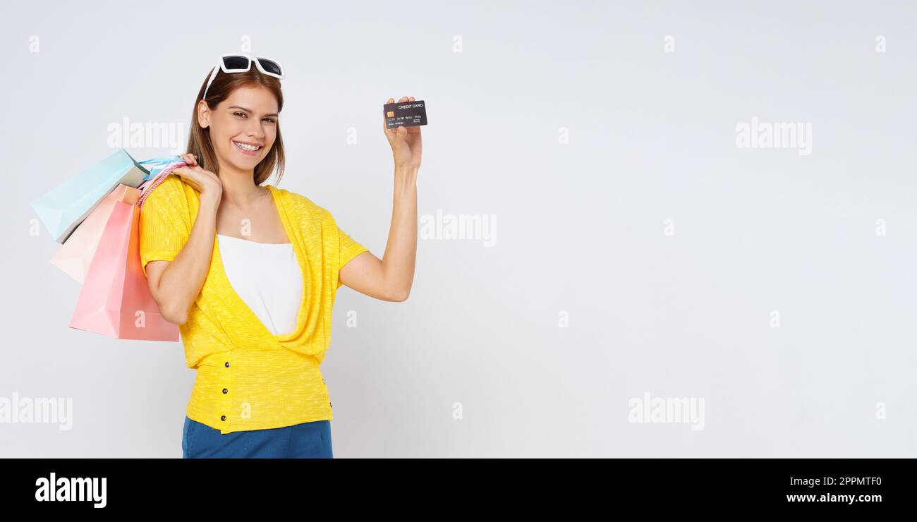 Felice giovane donna che tiene borse di shopping e mostrando carta di credito isolato su sfondo bianco. Foto Stock