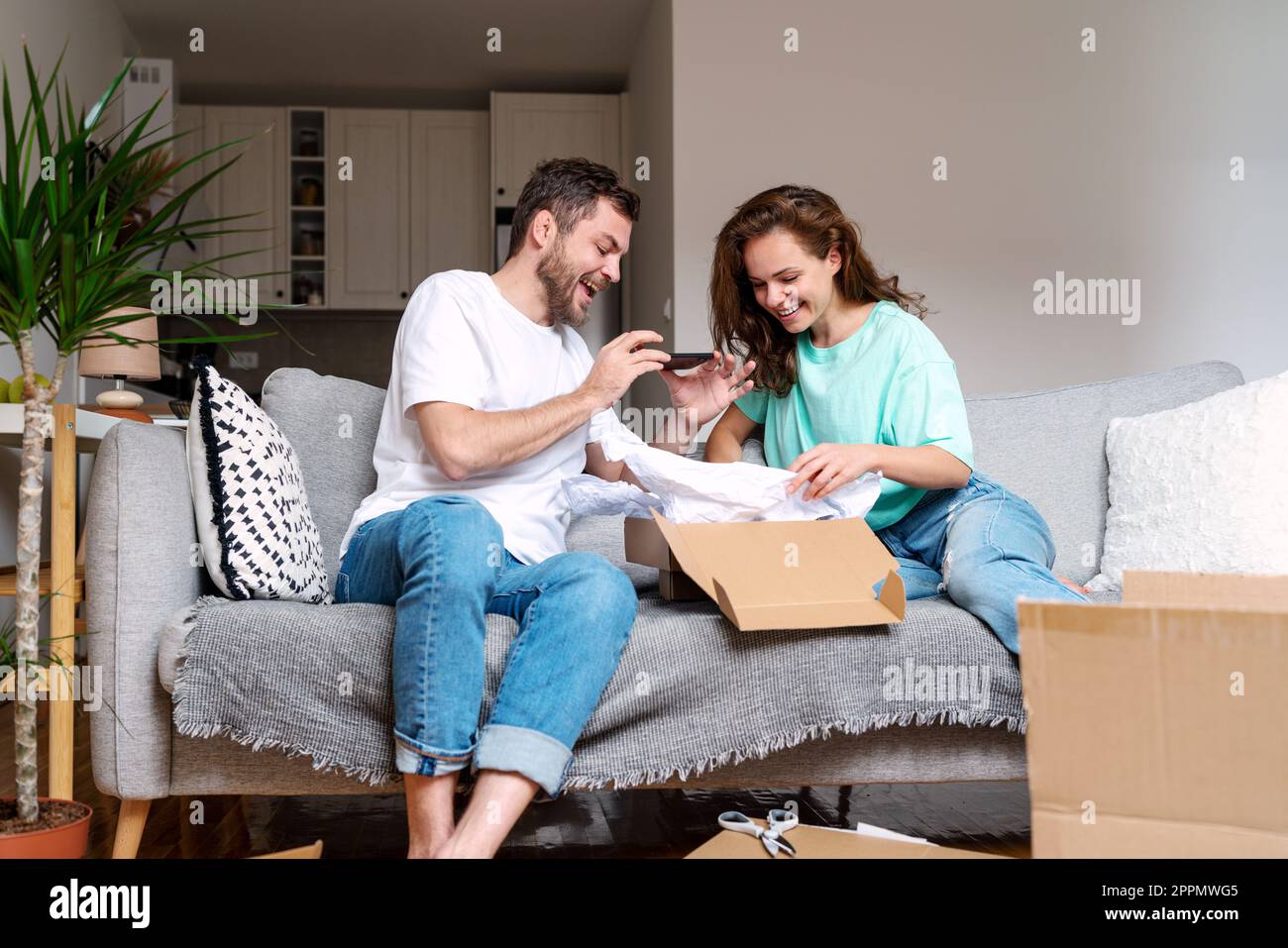 Giovane coppia che disinscatola il loro ordine del Internet dalla ferita in linea e fotografa l'acquisto per i loro mezzi sociali. Foto Stock