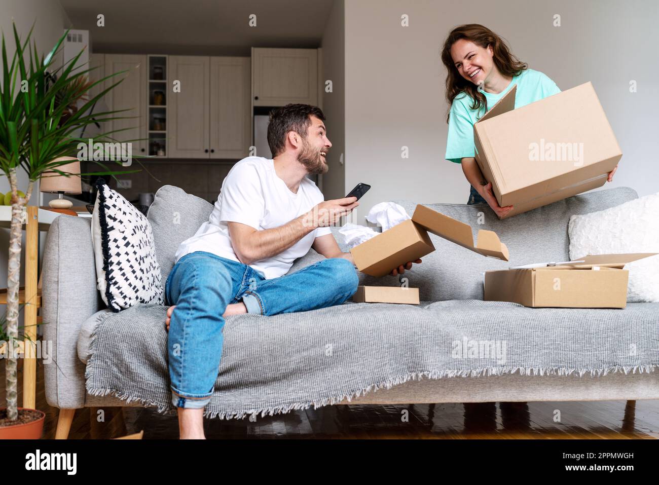 Giovane coppia sposata unboxing schede il loro acquisto del Internet, concetto domestico di shopping. Foto Stock