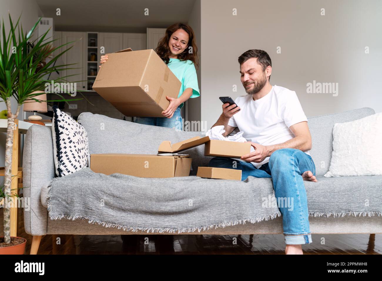 Giovane coppia unboxing schede il loro acquisto del Internet, concetto domestico di shopping. Foto Stock