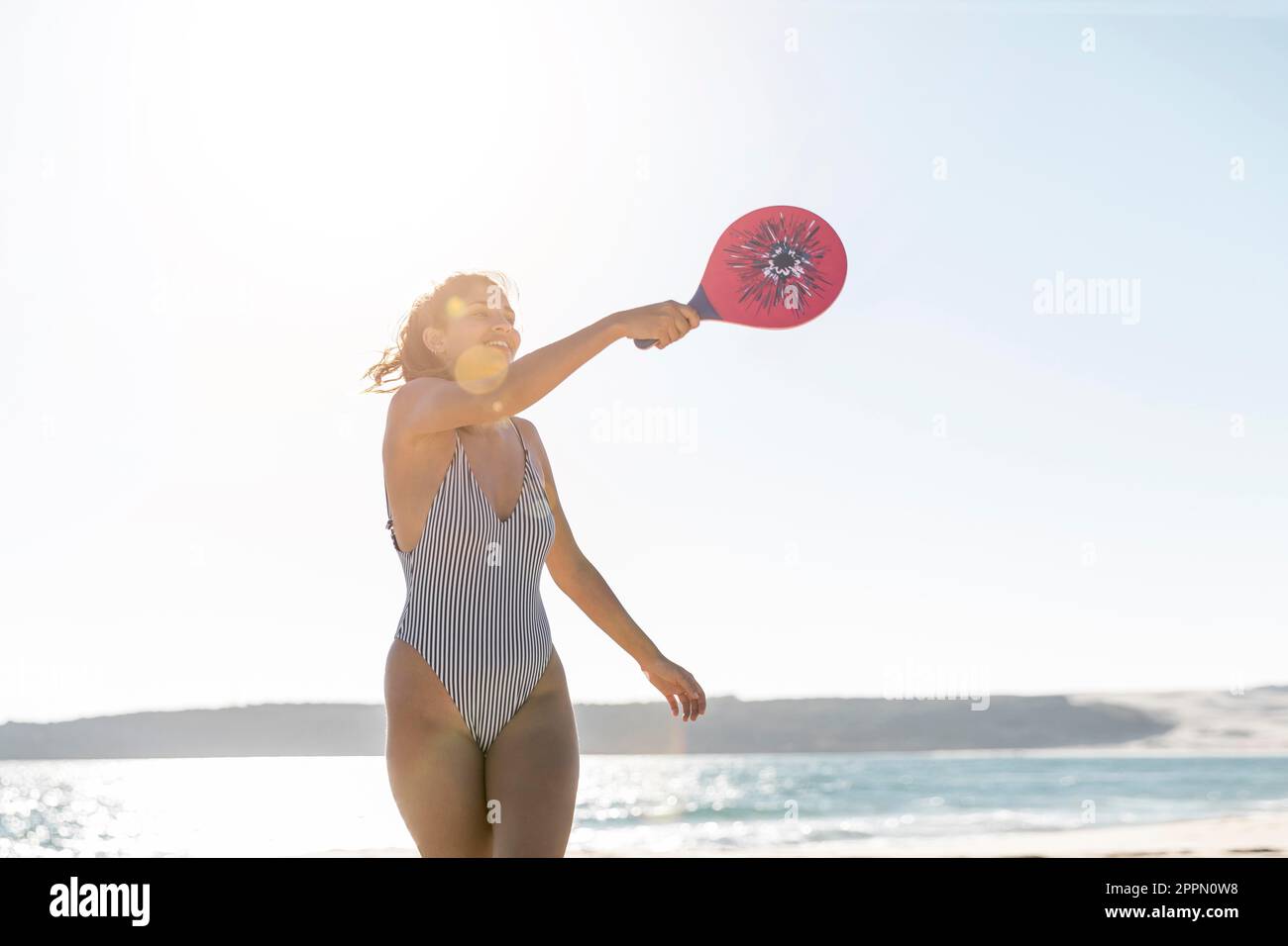 Giovane donna sorridente che gioca a tennis Foto Stock