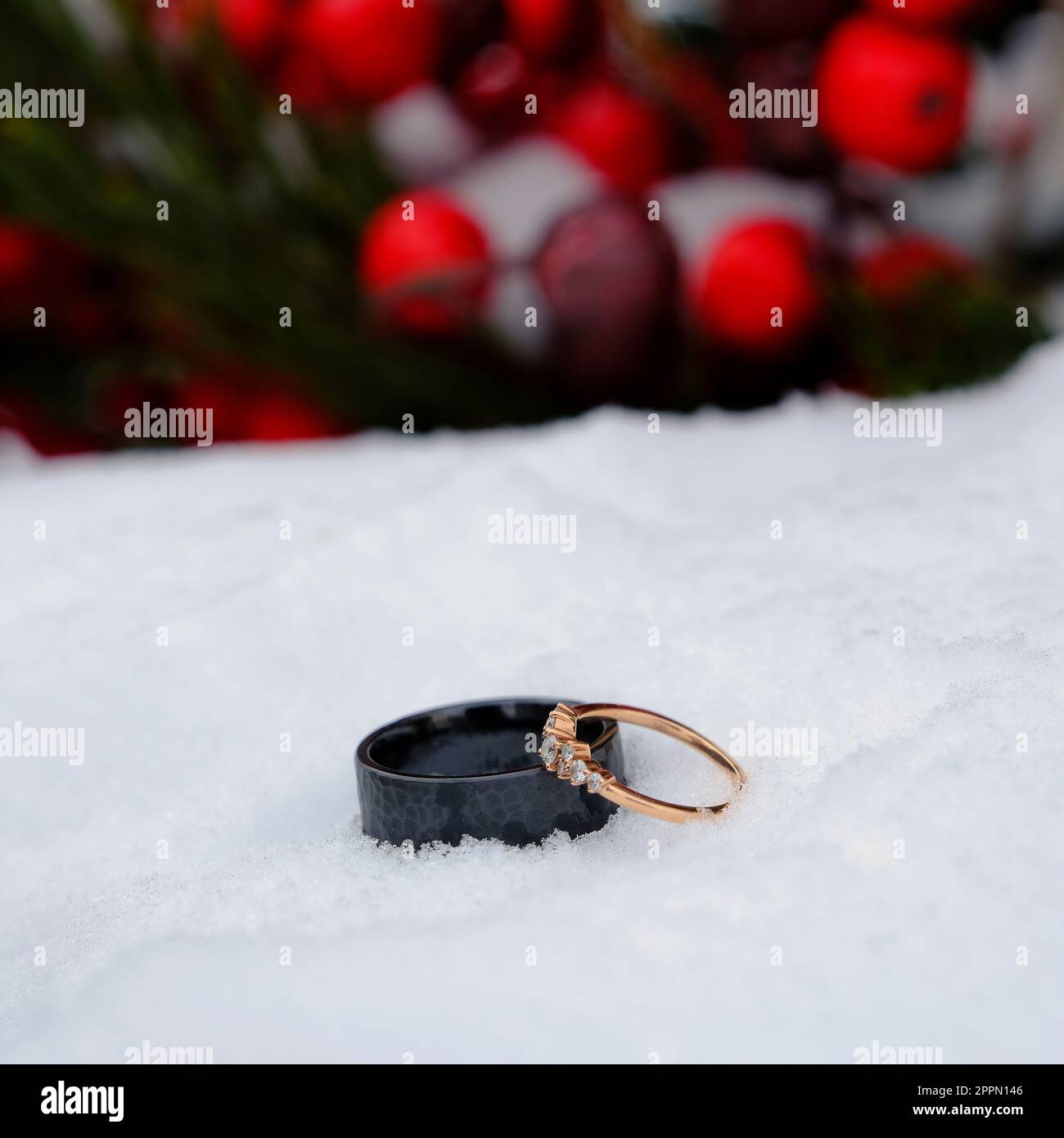 Anelli di nozze nella neve con la struttura rossa bacche simboleggia il matrimonio e l'impegno di rapporto Foto Stock