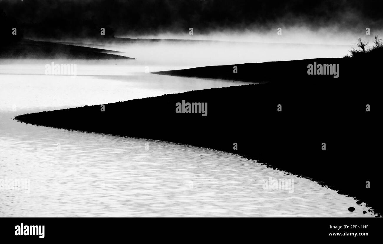 Misty mattina sul lago con vapore che si alza dall'acqua luce del sole Foto Stock