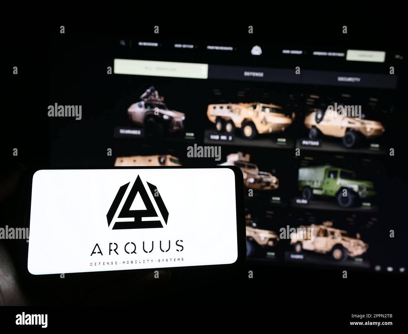 Persona che tiene il telefono cellulare con il logo della società francese di difesa Arquus SAS sullo schermo di fronte alla pagina web aziendale. Messa a fuoco sul display del telefono. Foto Stock