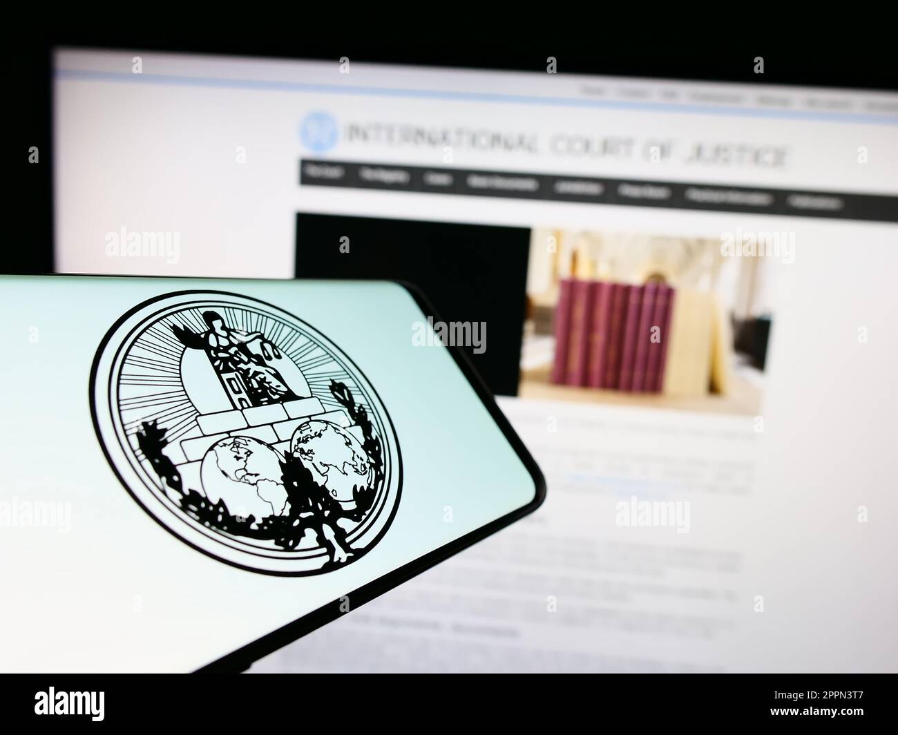 Smartphone con logo della Corte internazionale di giustizia (ICJ) sullo schermo di fronte al sito Web. Messa a fuoco al centro a destra del display del telefono. Foto Stock