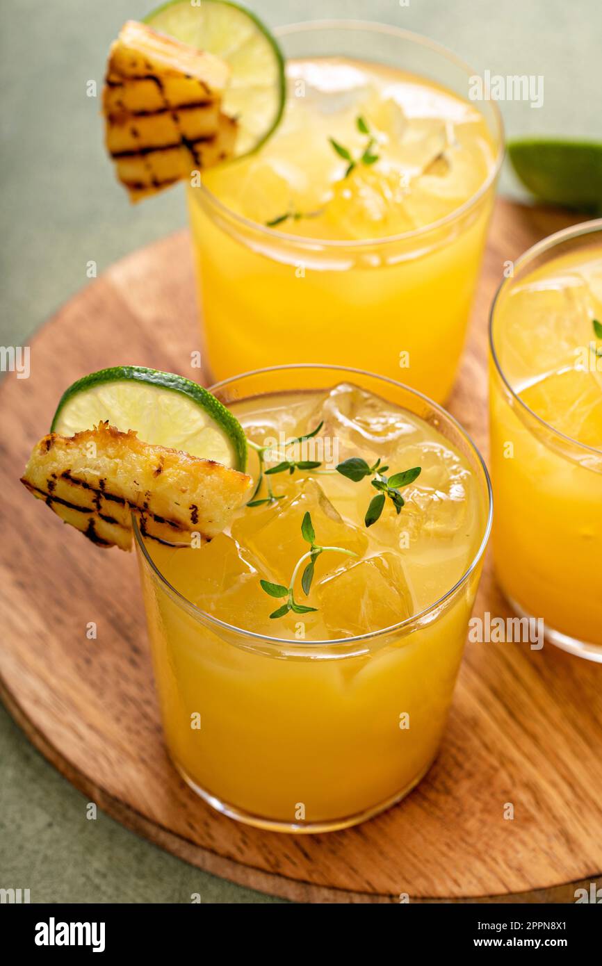 margarita di ananas alla griglia guarnita con spicchi di lime e timo Foto Stock