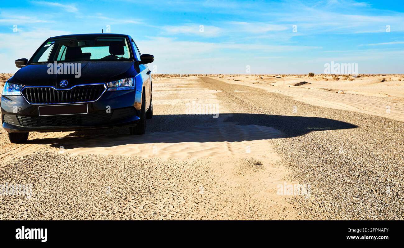 Douz, Tunisia, 12 gennaio 2023: L'auto nera si trova sul bordo della strada di ghiaia attraverso il deserto nel sud della Tunisia Foto Stock