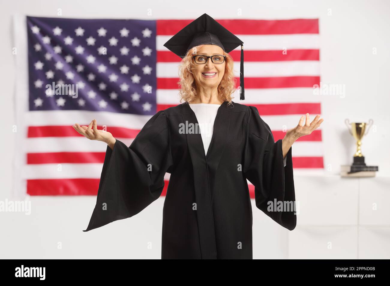 Professoressa universitaria in piedi di fronte a una bandiera degli Stati Uniti e gesturing con le mani Foto Stock