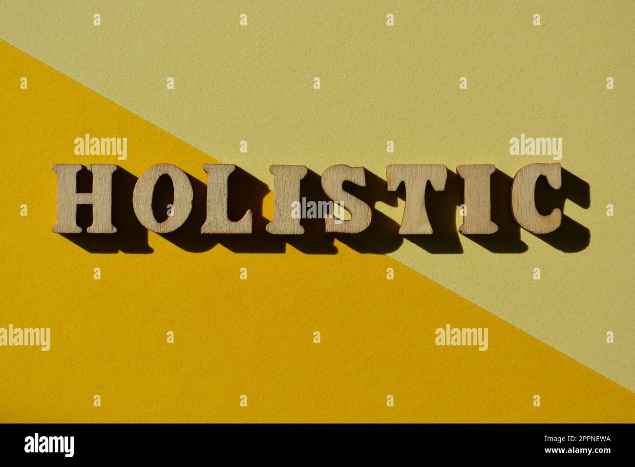 Olistico, parola in lettere di legno alfabeto isolato su sfondo giallo Foto Stock